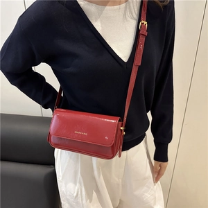 Glossy red square shoulder bag with adjustable strap and designer branding on flap