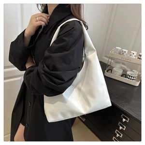 Minimalist white PU leather hobo tote bag worn with a black dress for a chic look