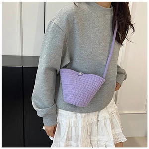 Close-up of purple knit bucket bag with a pearl buckle and textured crochet pattern