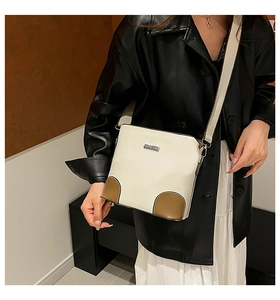 Detail of cream white bucket bag with brown contrast trim and wide woven shoulder strap