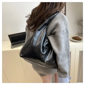 Minimalist black shiny leather tote bag shown on model for daily commuting style
