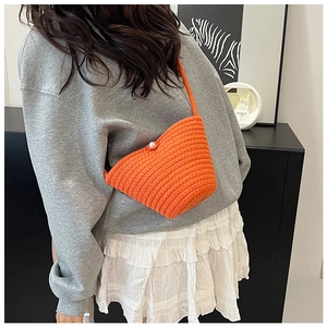 Detail of bright orange handmade woven bucket bag with elegant pearl button closure