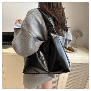 Glossy black hobo bag shown on shoulder in a minimalist and stylish home setting