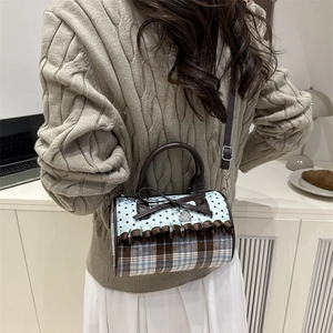 Sac à main cylindrique à carreaux avec nœud élégant porté avec une tenue d'automne