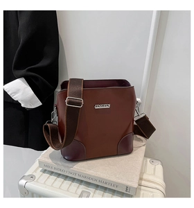 Detailed view of the dark brown leather bucket bag featuring a silver metal JINGPIN logo