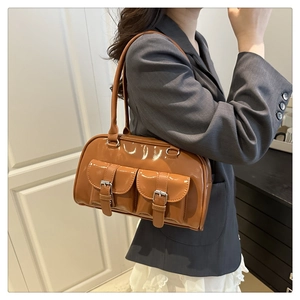 Close-up of shiny caramel brown underarm bag featuring double pockets and silver buckles