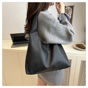 Minimalist black pebbled leather tote bag shown on model for a modern commute style