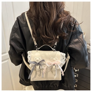 Détail du sac à dos en cuir crème avec bordures en dentelle et nœuds décoratifs