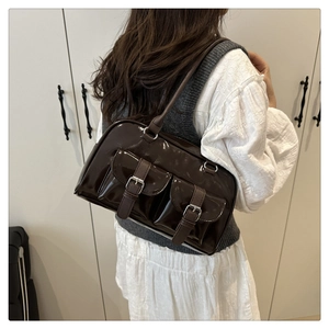 Detail of a dark coffee glossy underarm bag with silver buckles shown on a model