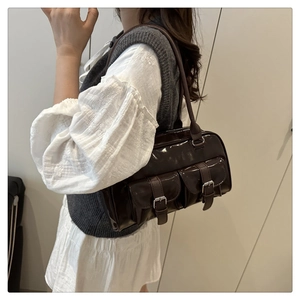 Detail of dark brown patent leather underarm bag with double front buckle pockets