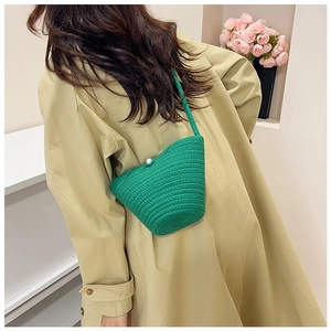 Green woven bucket bag with pearl clasp worn over a stylish khaki trench coat