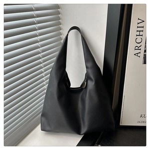 Detail of minimalist black pebble grain leather hobo bag with a sleek crescent silhouette