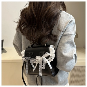 Vue détaillée du petit sac à dos en similicuir noir avec dentelle et nœuds