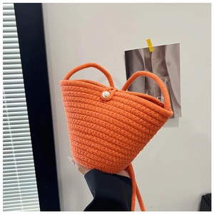 Detail of bright orange hand-woven bucket bag with honeycomb texture and pearl button