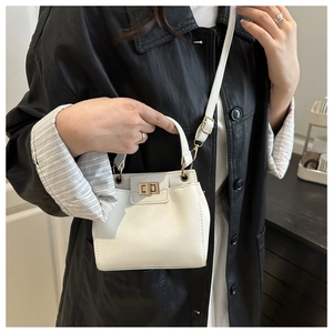 Close-up of white lychee-patterned bucket bag with gold twist lock on model in black leather jacket