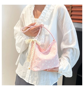 Détail d'un sac à main en tissu à carreaux roses avec fleurs et nœud en dentelle beige