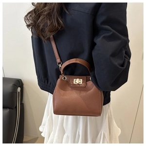 Detail view of brown pebbled leather bucket bag with gold twist lock and shoulder strap