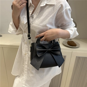 Minimalist black crossbody bag with large bow detail and adjustable strap for women