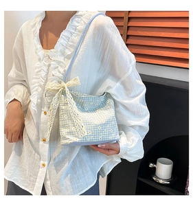 Détail du sac seau en tissu à carreaux bleu et blanc avec marguerites et nœud en dentelle