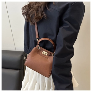 Close-up of brown lychee texture leather bag with gold twist lock on a shoulder strap