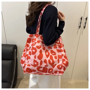 Close-up of pink leopard print canvas tote bag featuring a large front pocket and buckle