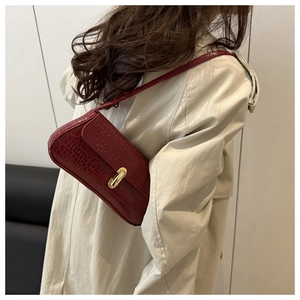 Detail of red crocodile texture baguette bag with gold buckle on a cream trench coat