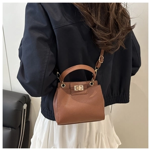 Crossbody view of brown pebble leather bucket bag with gold clasp and top handle