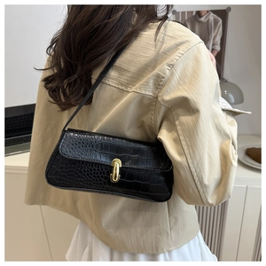 Detail of black crocodile texture underarm bag with gold U-shaped metal buckle on model