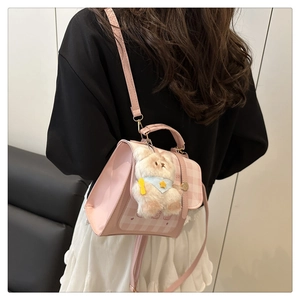 Pink patchwork crossbody bag with plush bear charm worn by a model in a casual setting