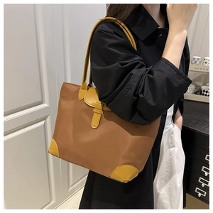 Detail of caramel nylon tote bag with bright yellow leather corners on shoulder