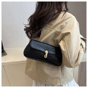 Detail of black crocodile pattern baguette bag with gold metal buckle on female model