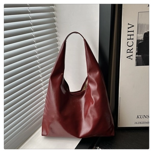 Detail shot of a glossy burgundy faux leather tote bag showing smooth surface texture