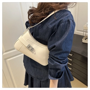 Détail d'un sac à bandoulière blanc crème avec boucle argentée porté par un mannequin
