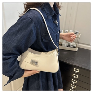 Détail du sac sous l'aisselle crème en cuir verni avec fermoir métallique argenté
