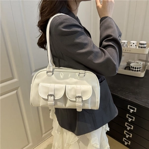 Chic white patent leather underarm pillow bag with dual front buckle pockets on a model