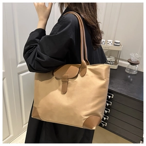 Detail of khaki tote bag featuring premium nylon fabric and brown leather trim accents