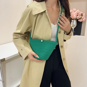 Green handmade woven bucket bag with pearl closure worn with a beige trench coat