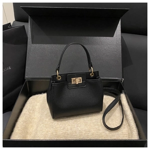 Detail of black pebbled leather bucket bag with gold turn-lock closure in a gift box