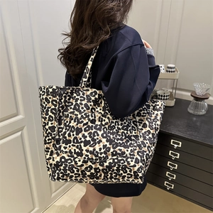 Leopard print tote bag with large front pocket, shown as a shoulder bag on a model