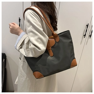 Detailed side view of large nylon tote bag with brown leather handles and buckle detail