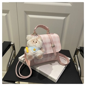 Detailed close-up of pink checkered crossbody bag with plush bear charm and metal buckle
