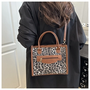 Detail of leopard print tote bag featuring brown PU leather handles and zipper pocket