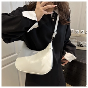 Adjustable silver buckle detail on white leather half-moon shoulder bag worn by model