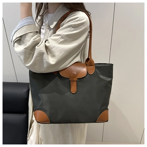 Detail of dark green nylon tote bag with brown leather handles and reinforced corners