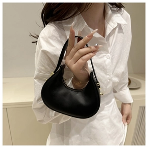 Detail of minimalist black leather croissant bag with gold zipper and metal hooks