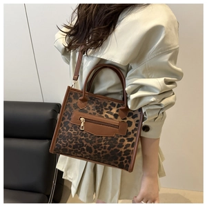Detail of leopard print tote bag with brown leather accents and gold zipper pocket