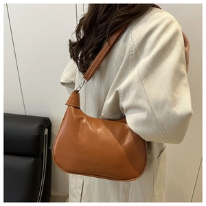 Detail of brown vintage dumpling bag with glossy leather finish and silver buckles