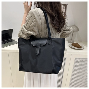 Black nylon tote bag with leather details in a modern lifestyle commute setting