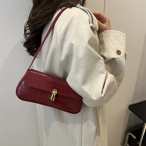 Burgundy crocodile embossed underarm baguette bag with gold buckle on model