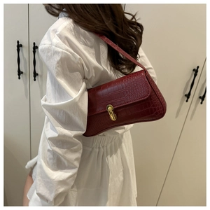 Detail of red croc-embossed underarm bag with gold metal lock on female model